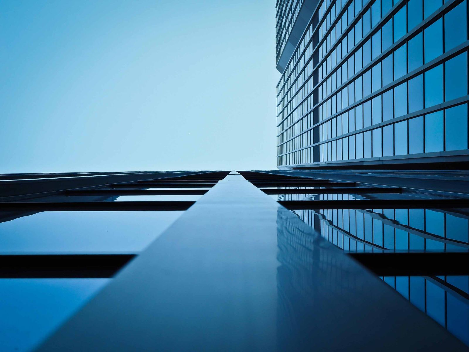 Façade d'un immeuble moderne en verre avec reflets, illustrant le nettoyage et l’entretien de bâtiments à Genève.